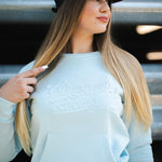 Woman wearing a white sweater and maroon cap standing on steps.